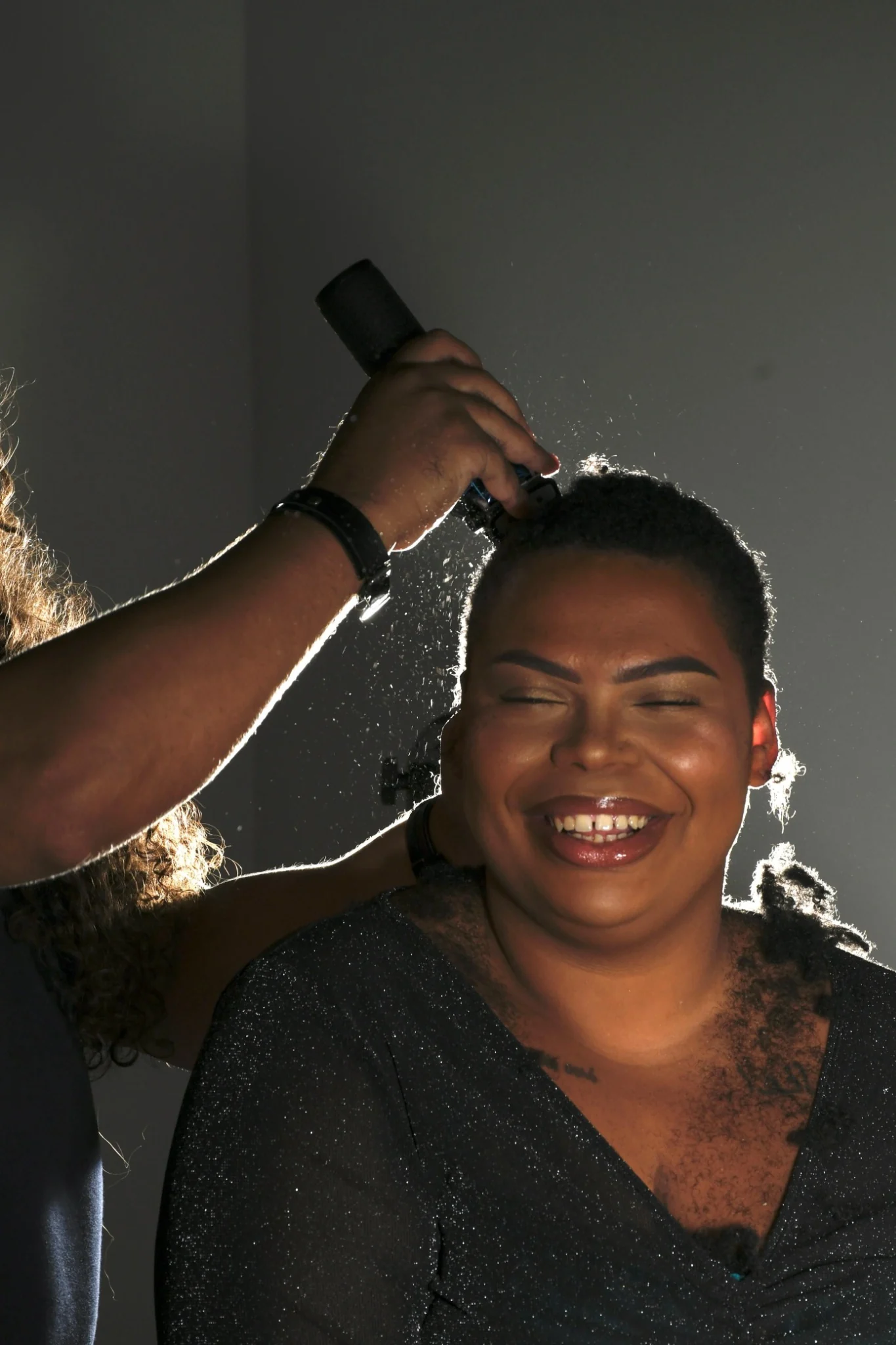 Hair professional styling a smiling client's short natural hair
