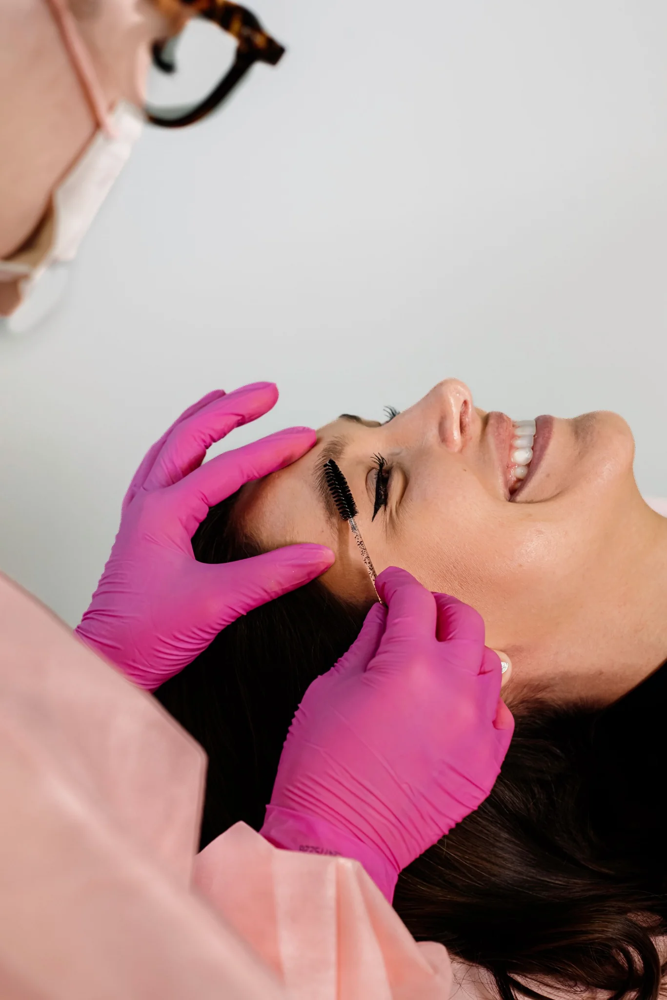 Beauty professional brushing a client's lashes and brows