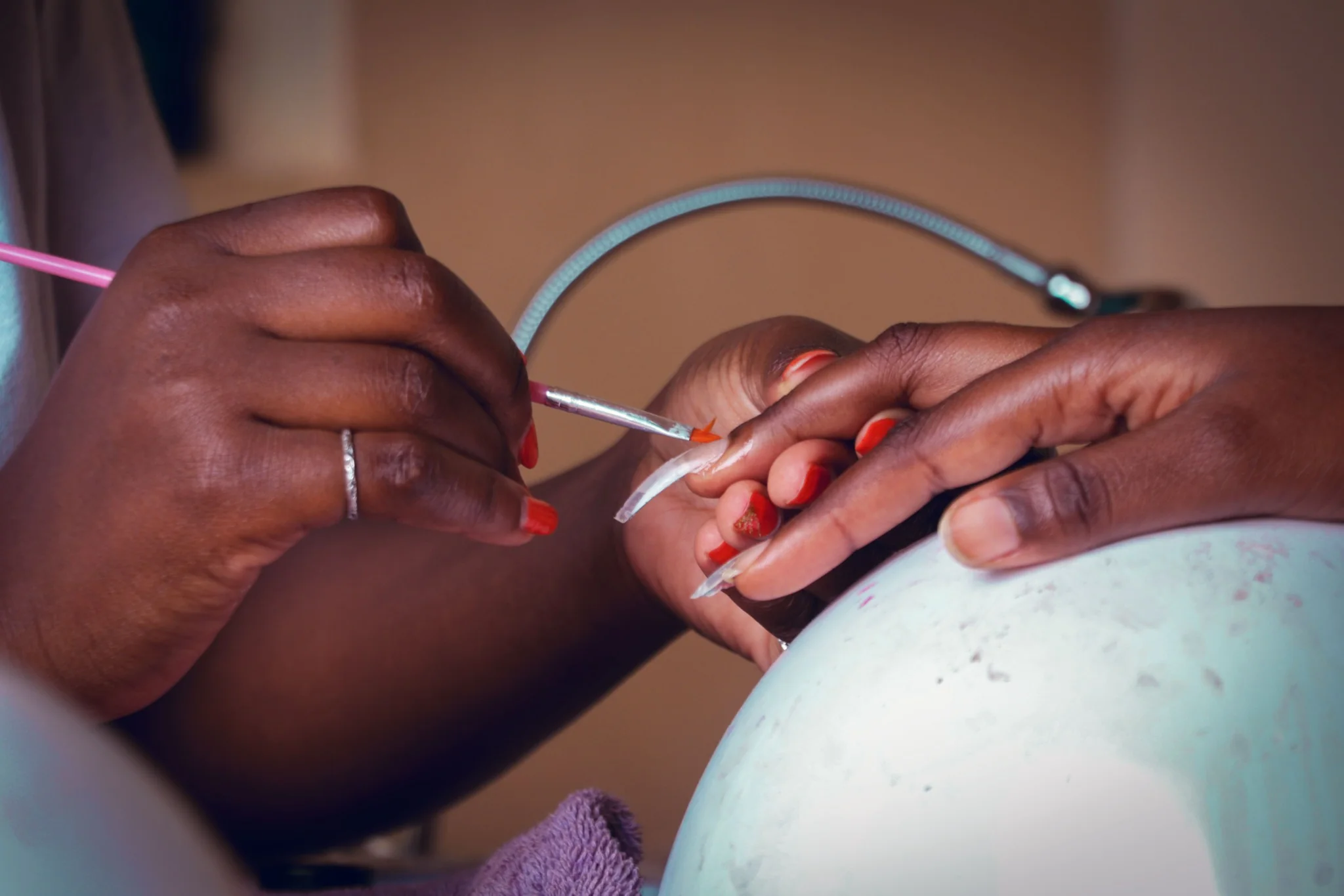 Nail technician painting a client's nails during a manicure.